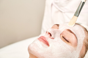 Naklejka premium Portrait of moisturizing clay mask for medical design. Woman skin procedure. Natural cosmetic products. Beauty face. Facial cosmetology treatment. Healthcare peeling cream