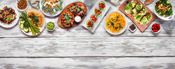 Healthy plant based low carb meal top border. Overhead view on a white wood banner background....