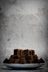 Delicious chocolate brownie on a white plate on a gray background