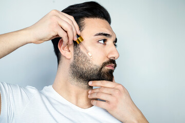 Obraz premium Bearded man holding pippete with beard oil 