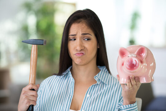 Frustrated Woman Breaking Piggy Bank With Hammer