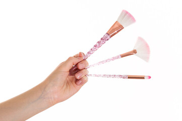 Makeup brush in a girl's hand on a white background