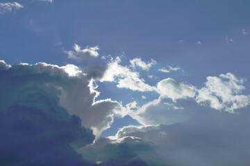 the clouds are white and blue against the blue sky illuminated by the sun