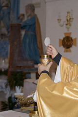 Holy host in the hands of the priest on the altar during the celebration of the mass and empty...