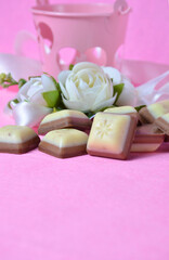 Decorative flowers and pieces of chocolate on a pink background. Valentine's Day