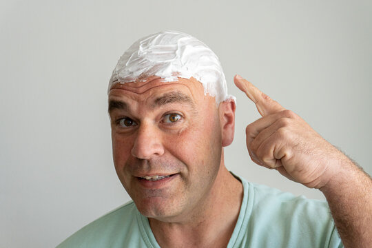 Close-up middle-aged Caucasian man with shaving foam spread, ready to shave his head.