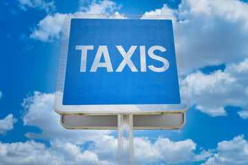 blue sign from France, with french word for cab in front of blue cloudy sky