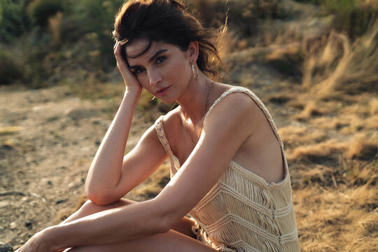 Beautiful lady wearing boho style clothes, relaxing on the meadow