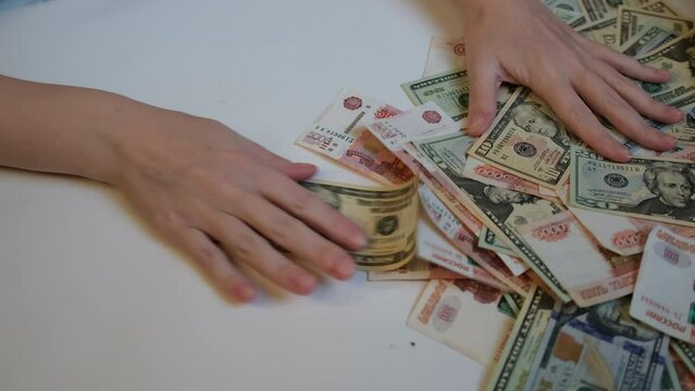 Women's hands give away a bunch of paper money and pull from themselves with American one hundred dollar bills, ten US dollars and Russian banknotes. Donate your money