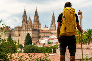 pilgrim looking at the cathedral of Santiago de Compostela in Spaink, backpack on his back. - obrazy, fototapety, plakaty