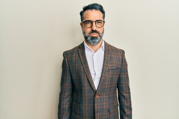 Middle age man with beard and grey hair wearing business jacket and glasses puffing cheeks with funny face. mouth inflated with air, crazy expression.