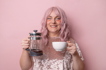 Attractive beautiful female woman hand holds hot cup coffee drink and teapot tea look at camera enjoying sunny morning isolated over pink wall background.