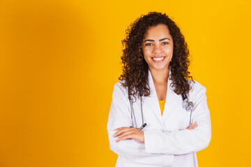 Smiling doctor woman on yellow background with arms crossed