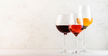 Red, rose and white wine glasses set on gray table background. Wine tasting. Hard light and harsh...