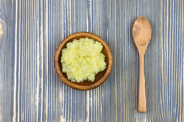 Millet porridge in a wooden plate on a wooden table.