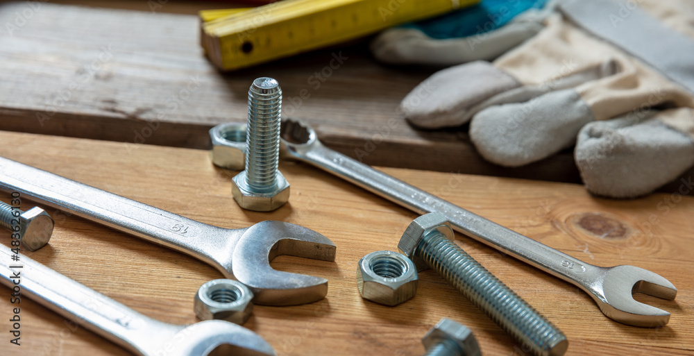 Wall mural spanner nut and boltl on wooden background. hand tool for repair and construction, closeup view