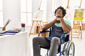 Young african american artist man sitting on wheelchair at art studio shouting and suffocate...