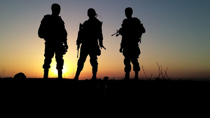 Silhouette of soldiers with weapons at sunset. High quality photo