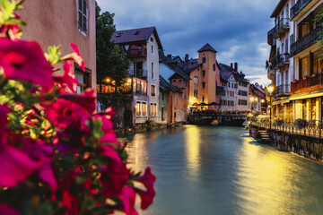 Fototapeta na wymiar city ​​view of Annecy in France at night on the banks of the river, with flowers in the foreground - Selective focus.