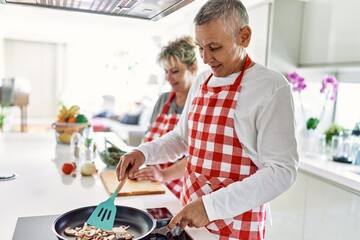 Senior caucasian couple smiling happy cooking at the kitchen.