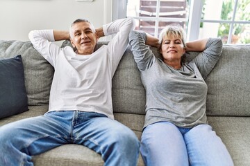 Senior caucasian couple smiling happy relaxed with hands on head sitting on the sofa at home.