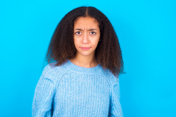 Fototapeta premium African teenager girl wearing blue sweater over blue background frowning his eyebrows being displeased with something.
