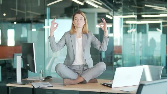 Businesswoman doing yoga to calm down the stressful emotion from hard work in office over desk with office. Business female, employee entrepreneur worker relaxation Meditation and rest in workplace