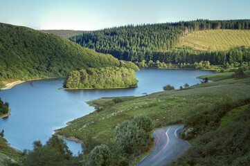 A landscape of the Elan Valley Reservoirs surrounded by greenery in Wales, the UK