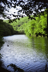 The Green Lake of Hamori in Lillafure near Miskolc, Hungary. Spring landscape with sunrays covering the mountains. The solar path on the water. Unrecognizable people on boat