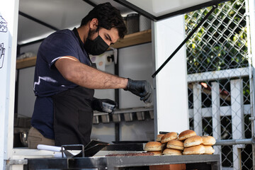 Chef seasoning and preparing hamburger on grill