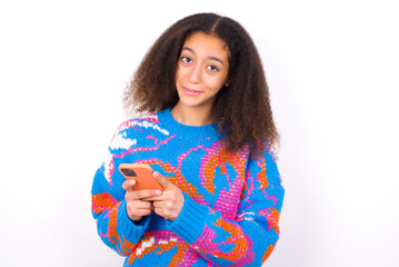 African teenager girl wearing colorful sweater over white background Mock up copy space. Using mobile phone, typing sms message