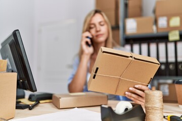 Young blonde woman ecommerce business worker talking on the smartphone at office