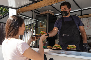 Food truck chef giving hamburger to customer