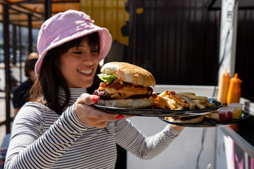 Woman about to eat burger next to a food truck
