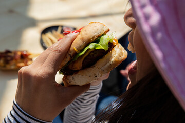 Woman hands holding burger outdoors