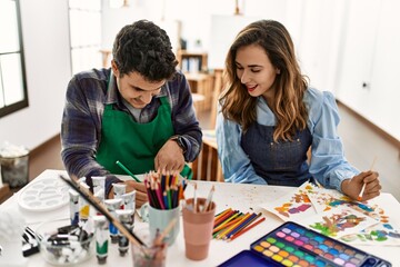 Fototapeta premium Two students smiling happy painting sitting on the table at art school.