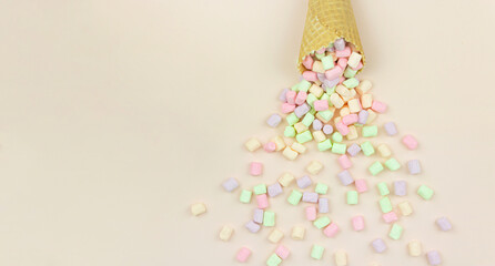 Delicious in the form of a waffle cone filled marshmallows on a pink background.