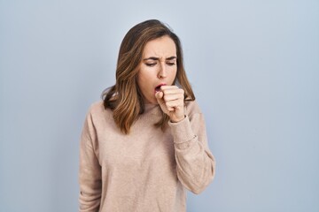 Young woman standing over isolated background feeling unwell and coughing as symptom for cold or bronchitis. health care concept.