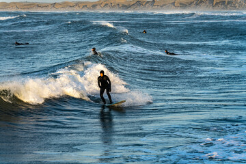 Surfer catching waves in cold water in winter, cold hawaii, norre vorupor, Klitmoller and Hanstholm, denmark - obrazy, fototapety, plakaty