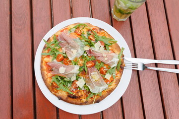 Pizza spezial mit einem Glas Rotwein im Biergarten