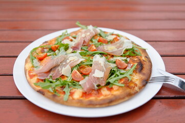 Pizza spezial mit einem Glas Rotwein im Biergarten