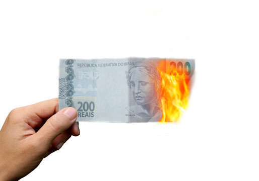 Flaming money in hand, isolated on white background. 200 reais Brasil. The concept of inflation, a decrease in the purchase of foreign currency, and devolution.