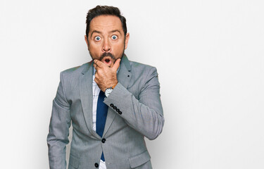 Middle age man wearing business clothes looking fascinated with disbelief, surprise and amazed expression with hands on chin