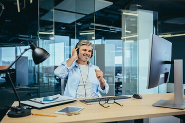 Senior and experienced business man resting at work during a break listening to music from...