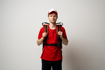 Delivery man in red t-shirt uniform work as dealer courier with a red thermal food bag isolated on white background studio. Food delivery service.