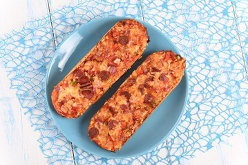 Baked baguette with cheese and sausage on a blue plate.