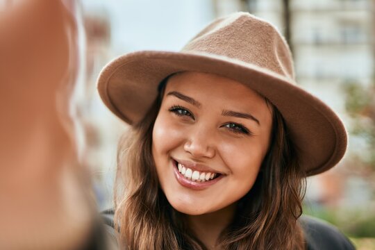 Young hispanic tourist woman smiling happy making selfie by the camera at the city.