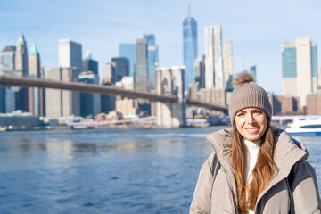 NEW YORK CITY WOMAN ENJOYING MANHATTAN VIEW FROM BROOKLYN PARK LIVING HAPPY DURING WINTER TIME IN UNITED STATES. TRAVEL, SUNNY DAY AND AMERICA CONCEPT. - obrazy, fototapety, plakaty