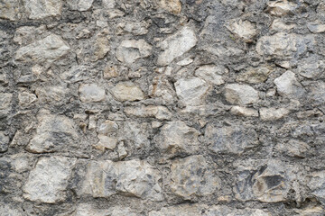 Full frame image of gray dirty stone wall. Rough pieces of marble and sandstone bonded with cement. Close-up stonewall texture for wallpaper or background, copy space