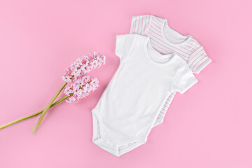 Two white baby bodysuit on pink pastel background. Empty place for text or logo on apparel. Mockup...